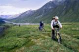 Bikers travel across the rough terrain and melt ice of southern Alaska's Alaska Range Mountains. 